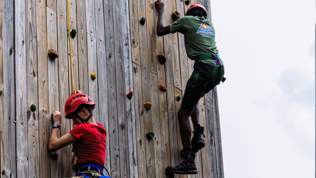 Trainees climb a challenge course wall