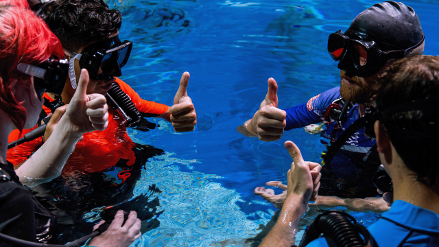 A group of trainees give thumbs up before diving into the Underwater Astronaut Trainer