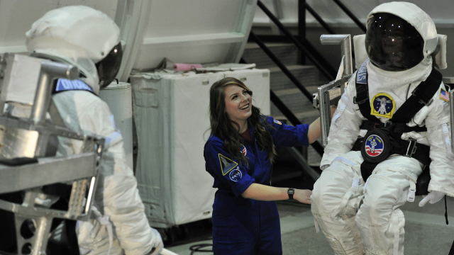 Two trainees in helmets and white extravehicular spacesuits participate in training activities